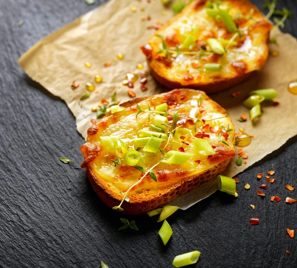Crostini com queijo derretido, cebolinha, pimentão e tomilho fresco — Fotografia de Stock
