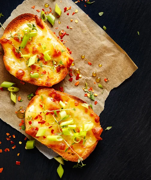 Small toast with melted cheese, scallions, chili peppers and fresh thyme — Stock Photo, Image