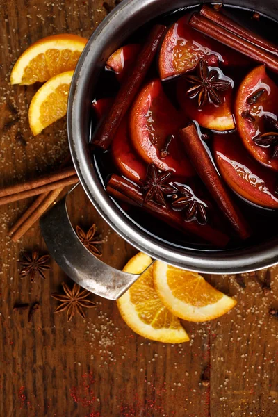 Vino tinto caliente con especias y naranjas en una olla —  Fotos de Stock