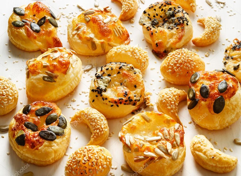 Cheese snacks with puff pastry sprinkled with a mix of seeds on a white