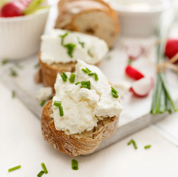 Canapés con queso cuajada y cebollino fresco sobre una mesa blanca. Desayuno delicioso y saludable —  Fotos de Stock
