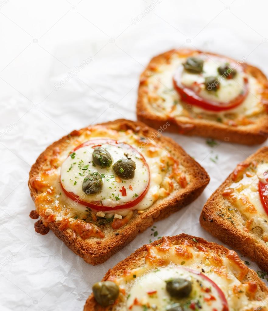 Bruschetta with cheese, tomatoes and capers on a white background