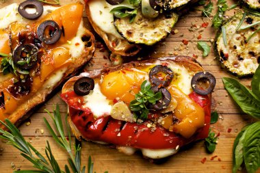 Bruschetta ızgara dolmalık biber, kabak, zeytin, taze otlar ve ahşap bir tahta üzerinde mozzarella peyniri ile