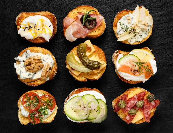 검은 배경에 다른 토 핑 Crostini — 스톡 사진