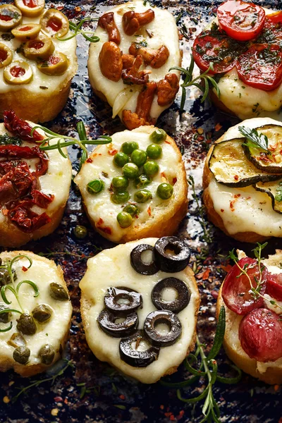 Crostini with different toppings on dark background. — Stock Photo, Image