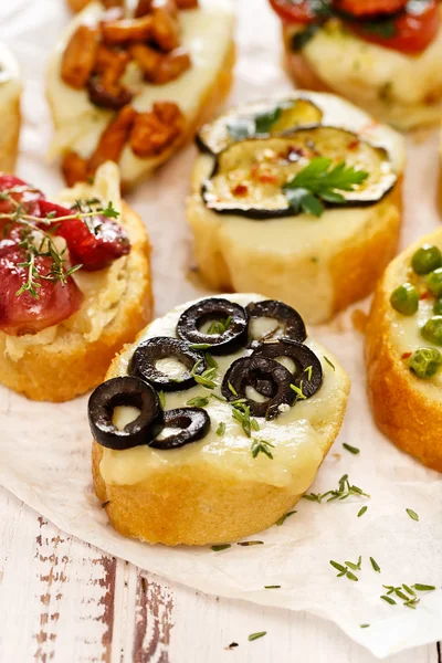 Crostini with addition of melted mozzarella cheese,  black olives and fresh thyme — Stock Photo, Image