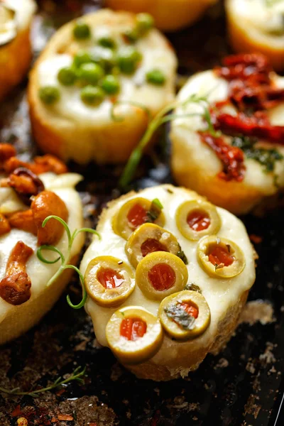 Crostini com adição de queijo mussarela derretido e azeitonas verdes — Fotografia de Stock