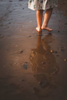 Anne ve kızı plajda gün batımında oynuyorlar.
