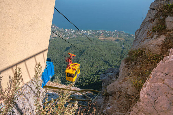 Высотная канатная дорога в горах Кавказа с кабиной, спускающейся к теплому Черному морю