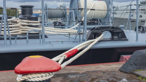 a powerful twisted anchor rope holds the warship docked at the pier