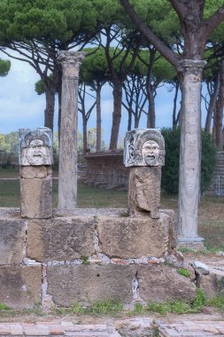 Eski İtalyan kenti Ostia Antica 'daki antik sütunlarda taş tiyatro maskeleri