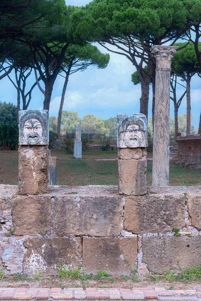 Eski İtalyan kenti Ostia Antica 'daki antik sütunlarda taş tiyatro maskeleri
