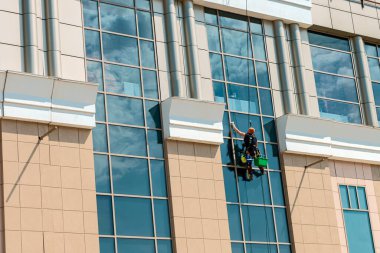 Endüstriyel tırmanışçı yüksek binaların camlarını temizliyor