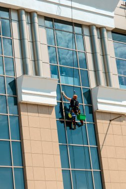 Endüstriyel tırmanışçı yüksek binaların camlarını temizliyor