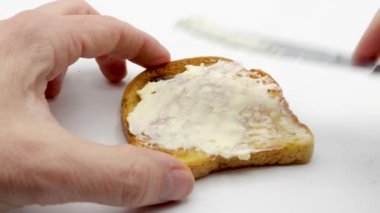Taze ekmek üzerine bıçakla tereyağı sürüyorum.