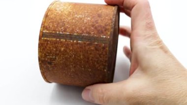 Beyaz arka planda eski ve paslı bir teneke kutu gösteriliyor