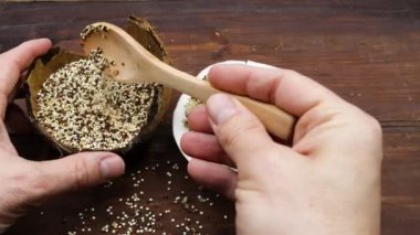 Üç renkli kinoalı ahşap kaşık ve çiğ kinoalı hindistan cevizi.