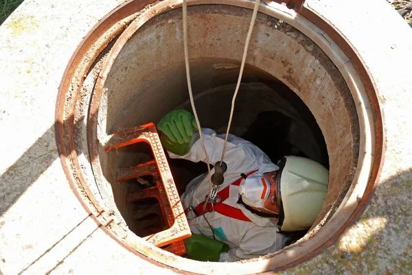 Bir yeraltı teknisyeni şehrin atık suyunu incelemek için kanalizasyonu inceliyor.