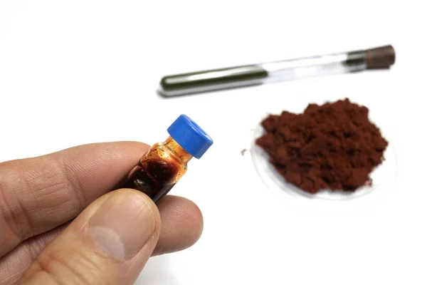 Beyaz arka planda toz halinde Sangre de drago adı verilen parmak izi geliştirmek için kullanılan bir reaktör gösterilir ve sıvı halde bir şişede çözünür, tıpta iyileştirici özellikleri vardır.