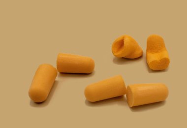 Orange colored foam ear plugs to prevent ambient noise on orange background