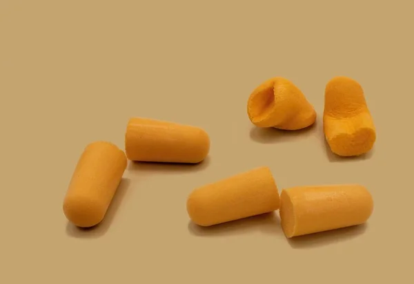 Orange colored foam ear plugs to prevent ambient noise on orange background