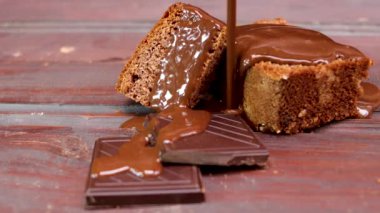  Sünger kekin üzerine çikolata dökmek, erikli kek ve kahverengi ahşap arka planda iki parça çikolata.
