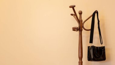 Siyah El Çantası Klasik Ahşap Ceket Rafında Boş Bej Duvara Karşı Asılı
