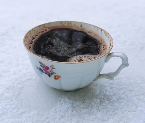 Closeup a cup of black coffee in the snow