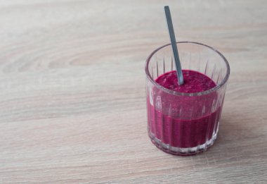 Böğürtlen kokteyli (smoothie) bir bardakta ve tahta bir masada metal kaşıkla