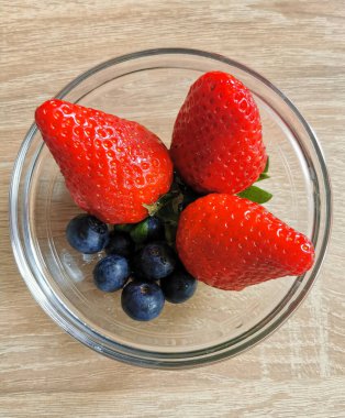 Bir cam kasede yaz meyveleri, çilekler ve yabanmersini koleksiyonu.