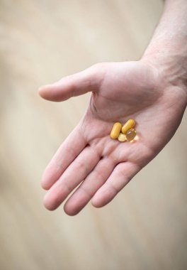 Vitaminler ve takviyeler. Adam tabletleri sağ elinde tutuyor. Sağlık, yardım ve tıp kavramını temsil eden haplar