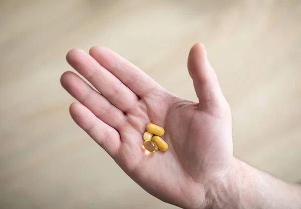 Vitamins and supplements. The man is holding the tablets in his right hand. Pills in hand representing health, help and medicine concept