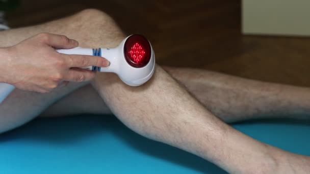 那个人用电热灯按摩他生病的膝盖 — 图库视频影像
