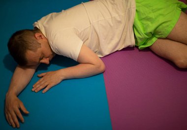 Adam bilinçsiz yatıyor. İlk yardım ve iyileşme pozisyonu. Ağız aşağı doğru, böylece sıvı hastanın solunum yolundan çekilebilir. Kollar ve bacaklar hastanın durumunu sabitlemek için kilitlendi.