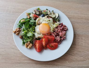 Sağlıklı ve lezzetli bir yaz kahvaltısı. Yumuşak yumurta, karabuğday inlemeleri, renkli sebzeler ve fındıklar.