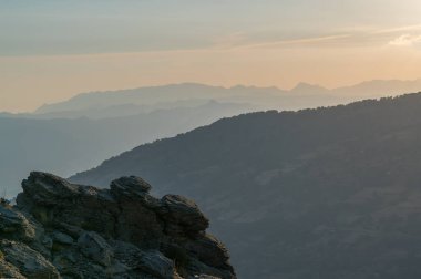Güney İspanya 'nın dağlarında gün batımı, dağlarda ağaçlar var ve gökyüzünde turuncu bulutlar var.