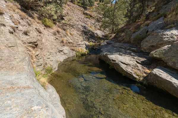 在内华达州的内华达山脉 水流下了一个峡谷 那里有一潭晶莹清澈的水 那是一个岩石区 岩石上有草 天空晴朗 — 图库照片