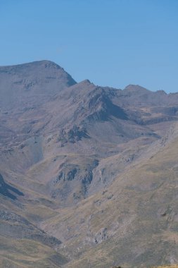 Güney İspanya 'da Sierra Nevada' nın dağlık arazisi. Yerde bitki örtüsü var. Gökyüzünde bulutlar var.