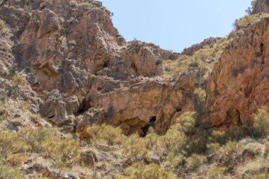 İspanya 'nın güneyindeki dağlık arazi, dağlarda büyük kayalar, çalılar ve ağaçlar var, gökyüzü açık.