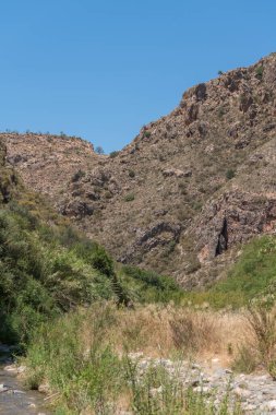 İspanya 'nın güneyindeki dağlık arazi, dağlarda büyük kayalar, çalılar ve ağaçlar var, gökyüzü açık.