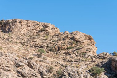 Güney İspanya 'nın dağlık arazisi, dağlar kayadan yapılmış ve çalıları var, ağaçlar var, gökyüzü açık.