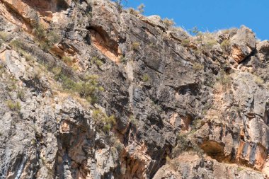 Güney İspanya 'nın dağlık bir bölgesinde kayalık bir uçurum var, çalılar var ve gökyüzü açık.