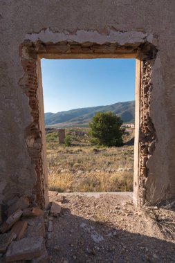 Eski bir maden kompleksinin içi tuğladan yapılmış, bir kapı var ve bir ağaç, birkaç bina ve bir ağaç var, gökyüzü temiz.