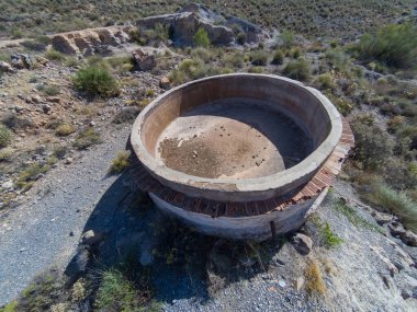 Güney İspanya 'daki eski maden kompleksi, beton blokta bazı cıvatalar var, taş bir duvar var, bitki örtüsü var.