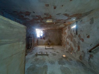 Eski bir elektrik transformatörünün içi, tuğladan yapılmış, birkaç penceresi var ve tavanında bir delik var.