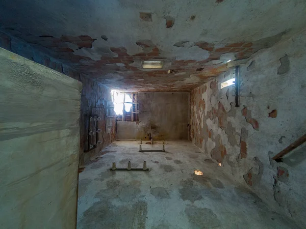 Eski bir elektrik transformatörünün içi, tuğladan yapılmış, birkaç penceresi var ve tavanında bir delik var.