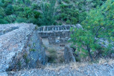 Sierra Nevada 'daki eski harabe değirmen, değirmen taştan yapılmış, ağaçlar ve kuru çimenler var.