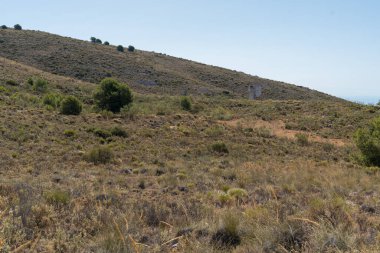 Güney İspanya 'nın dağlık bölgesi. Ağaçlar ve çalılar var. Eski bir bina var.