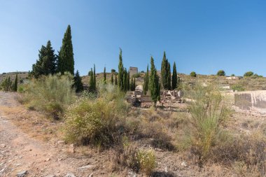 Güney İspanya 'da terk edilmiş bir maden tesisinde inşaat, inşaat beton ve taştan yapılmış, çalılar ve ağaçlar var, gökyüzü açık.