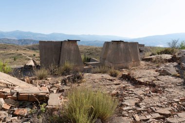 Güney İspanya 'da terk edilmiş bir maden tesisinde inşaat taş, tuğla ve betondan yapılmıştır. Ağaçlar ve çalılar vardır. Gökyüzü açıktır.